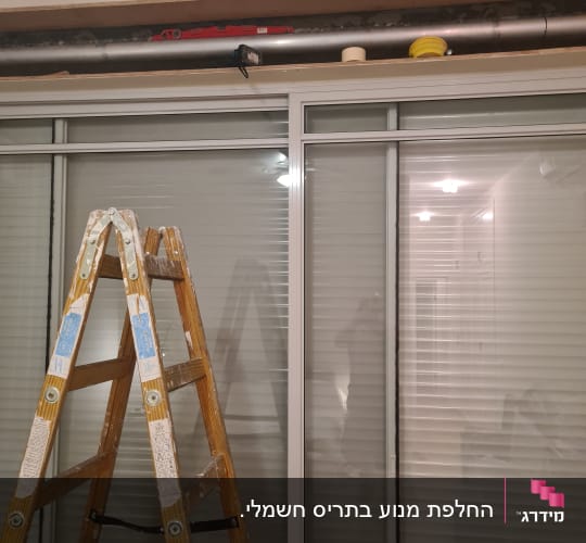 סולם עץ מול תריסים סגורים עם צינור מעל